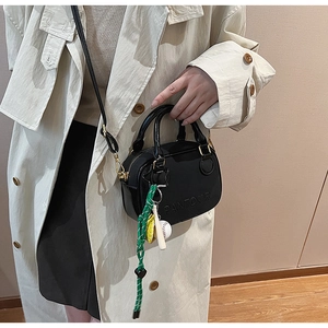 Detail of black mini crossbody bag with embossed logo and baseball charm accessory