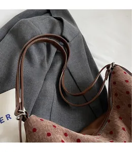 Adjustable brown leather strap with metal buckle detail on a polka dot tote shoulder bag