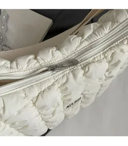 Détail de la fermeture éclair argentée sur un sac matelassé beige au design moderne