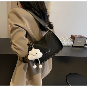 Detail of black nylon pillow bag with wide strap and white plush cloud charm accessory