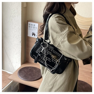 Detail of black glossy leather underarm bag with white text print and silver chain