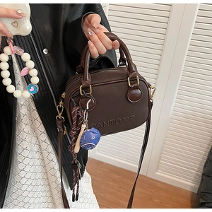 Close-up of brown crossbody bag featuring embossed Pantoor logo and baseball charm