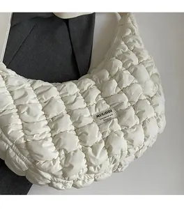Détail du tissu gaufré blanc et de l'étiquette sur le sac à bandoulière demi-lune
