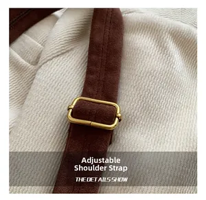 Detail of adjustable dark brown suede strap with gold metal buckle on corduroy fabric