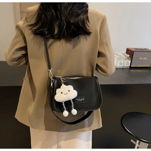 Detail of black leather pillow bag with cute cloud charm worn over a khaki blazer