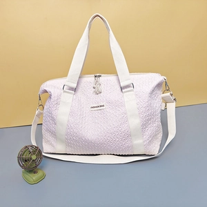 Light purple quilted travel bag with white handles and detachable shoulder strap