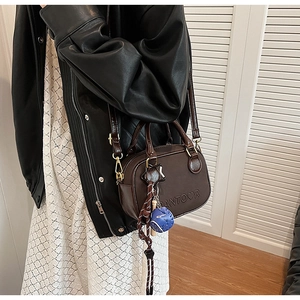 Detail of dark brown faux leather handbag with embossed letters and decorative charms