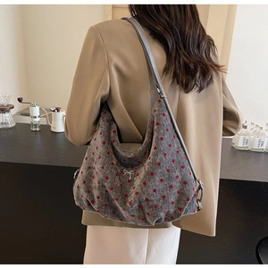 Close-up of grey suede tote bag with red polka dots and silver metal bow detail