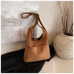 Detail of caramel suede bucket bag featuring magnetic closure and premium stitching