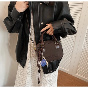 Détail macro du sac en cuir marron avec lettrage embossé et breloques de baseball