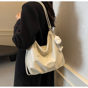 Détail d'un grand sac hobo blanc crème avec un charm en peluche nuage sur la bandoulière