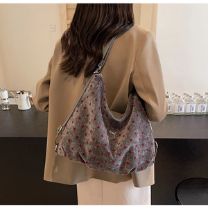 Grey suede tote bag with red polka dots and silver bow detail on a casual suit