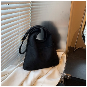Detail view of black faux suede crossbody bag with adjustable strap and golden buckle