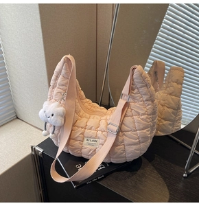 Détail du sac croissant matelassé rose clair avec étiquette et breloque nuage