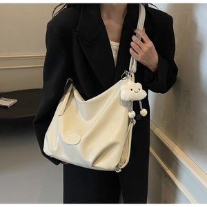 Détail d'un grand sac cabas blanc cassé porté à l'épaule avec un pendentif nuage en peluche