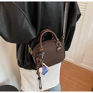 Detail of coffee leather handbag with embossed PANTOOR logo and cute charms on handle