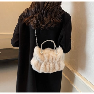 Detail of cream faux fur cloud bag featuring rhinestone handle and pearl accents