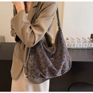 Detailed view of grey polka dot shoulder bag with silver bow charm on a female model