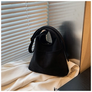 Detail of vintage black bucket bag showing matte canvas texture and retro gold hardware