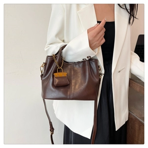 Detail of dark brown leather bucket bag with contrast mini pouch charm and shoulder strap