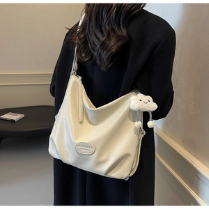 Détail du grand sac cabas blanc cassé avec écusson logo et breloque nuage en peluche