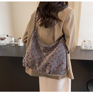 Close-up of grey corduroy hobo bag with red polka dots and a silver bow on a strap