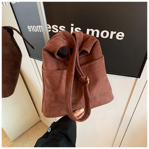 Close-up of brown faux suede bucket bag showing side pockets and gold metal buckle detail