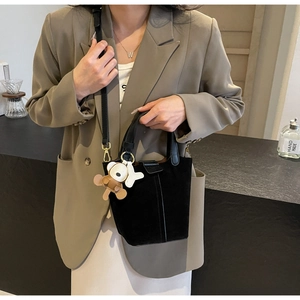 Detail of black bucket bag featuring suede texture and cute bear charm accessory