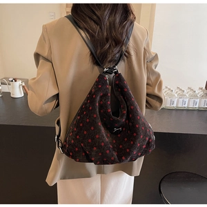 Detailed close-up of a vintage red polka dot pattern on a soft corduroy shoulder bag
