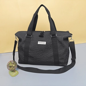 Black travel bag with diamond quilted texture, top handles and adjustable shoulder strap