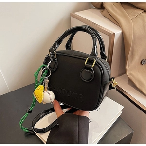 Detail of black mini square bag with embossed logo and baseball charm accessory