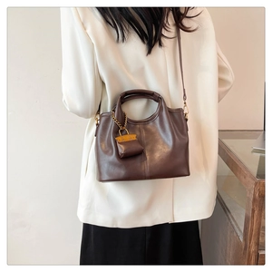 Detail of a dark brown matte leather bucket bag featuring vertical stitching and a mini pouch