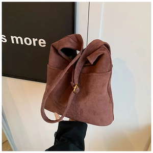 Detail of dark brown suede bucket bag with side pocket and adjustable gold buckle strap
