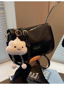 Minimalist black nylon crossbody pillow bag with a plush cloud charm and leather trim
