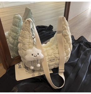 Détail du sac matelassé beige avec bandoulière tressée et charm peluche sur soie noire