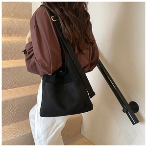 Black large capacity crossbody bucket bag with wide strap and gold hardware on model