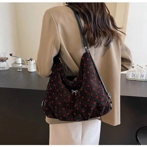 Close-up of brown velvet tote bag with red polka dots and a silver bow buckle accent