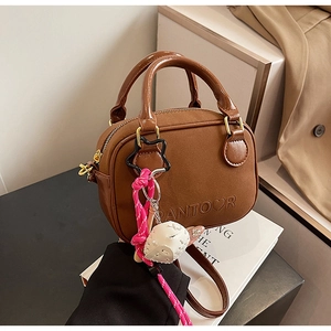 Detailed view of a brown leather crossbody bag with brand embossing and unique charms