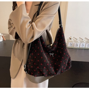 Polka dot shoulder bag with silver bow detail shown on a model for scale