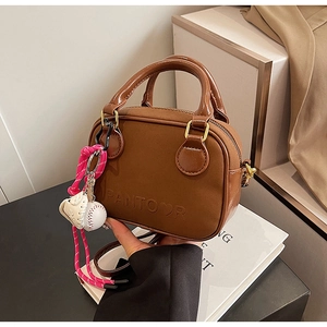 Close-up of brown faux leather mini bag with embossed lettering and baseball charms