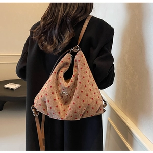 Polka dot hobo bag featuring a metallic bow detail and brown leather shoulder strap