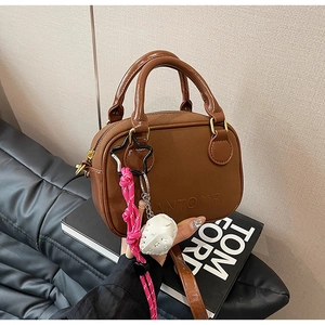 Gros plan d'un sac à main en cuir marron avec texture gaufrée, breloque étoile et zip doré