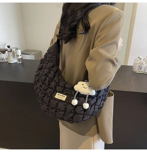 Détail d'un sac nuage matelassé noir avec un charm en peluche mignon et étiquette de marque