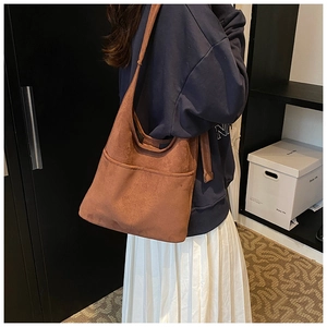 Side view of a dark brown suede hobo bag with front pocket shown on a female model