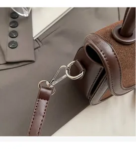 Détail du sac selle marron en cuir lisse avec fermoir mousqueton en métal argenté élégant