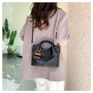 Chic black bucket bag with contrast orange charm shown on a lavender blazer model
