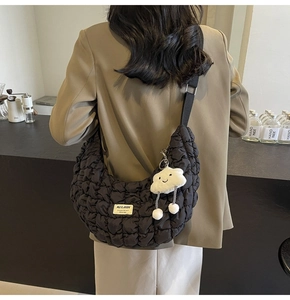 Détail du sac dumpling noir matelassé avec texture bulle et charm nuage en peluche