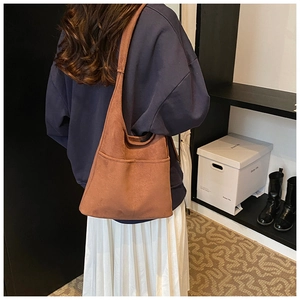 Brown faux suede tote bag with front pocket shown on a model in a casual outfit