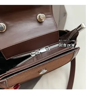 Détail du sac besace marron foncé avec fermeture éclair argentée et texture en daim