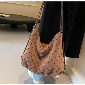 Detailed side view of brown corduroy tote with red polka dots and metal bow charm